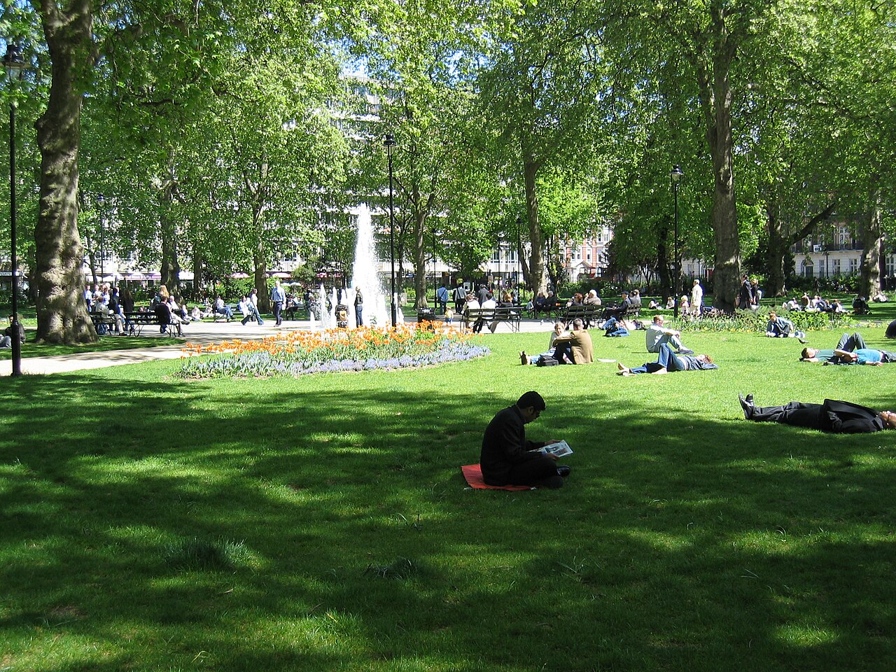 People reading and relaxing around the fountain in Russell Square